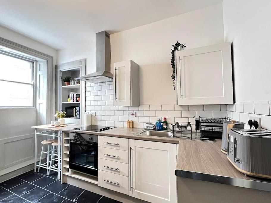 una cucina con armadi bianchi e piano di lavoro di Little Dockray 1 Bed Apartment a Penrith