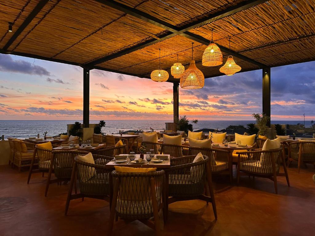 a restaurant with tables and chairs with a sunset in the background at Secana Beachtown Resort & Residences in Canggu