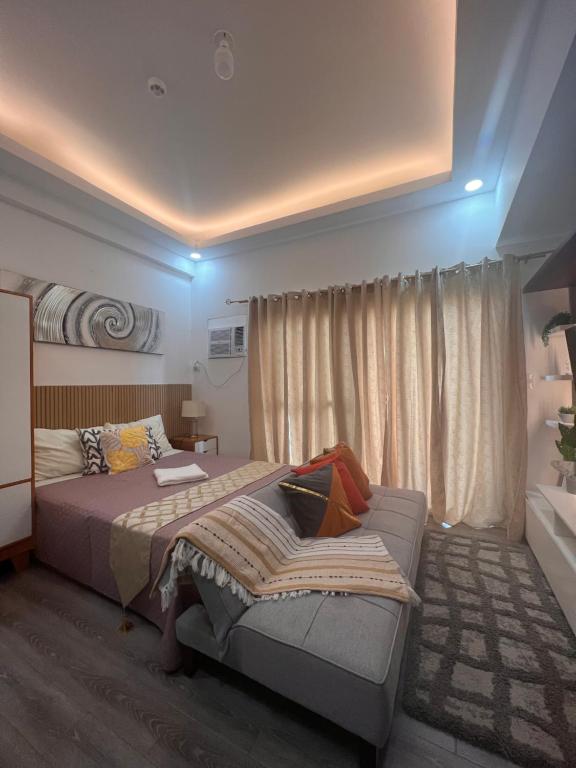 a bedroom with a bed and a couch in it at Amani Grand Citygate at the back of Gaisano Milan in Davao City