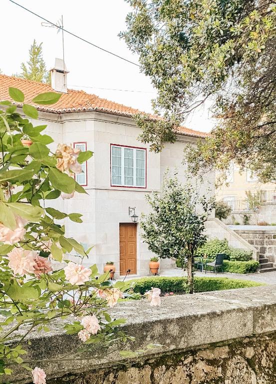 a white house with a brown door and pink flowers at Quinta Costa da Estrela in Gouveia