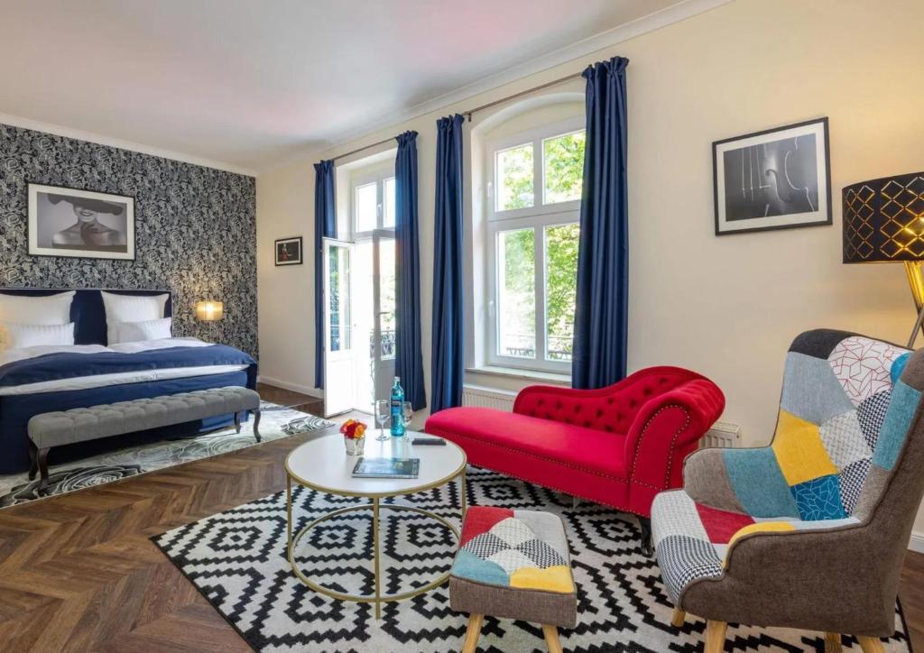een woonkamer met een bed en een rode stoel bij Schlosshotel Rheinsberg in Rheinsberg
