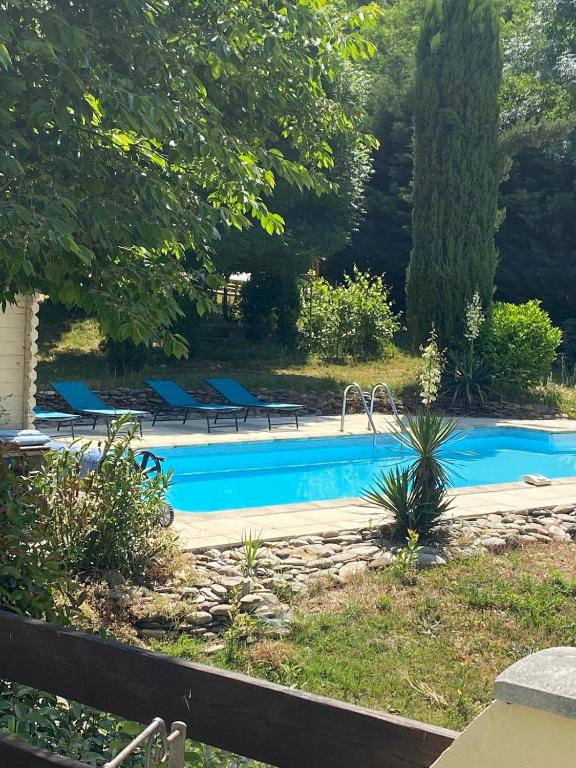 - une piscine dans une cour avec des chaises bleues dans l'établissement Maison avec piscine entre Gard et Ardèche, à Gagnières