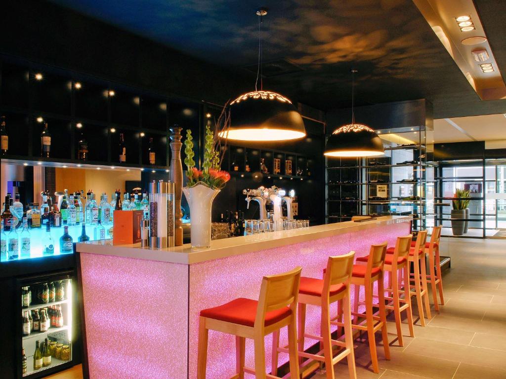 un bar avec des chaises orange et un comptoir rose dans l'établissement Mercure Hotel Den Haag Central, à La Haye