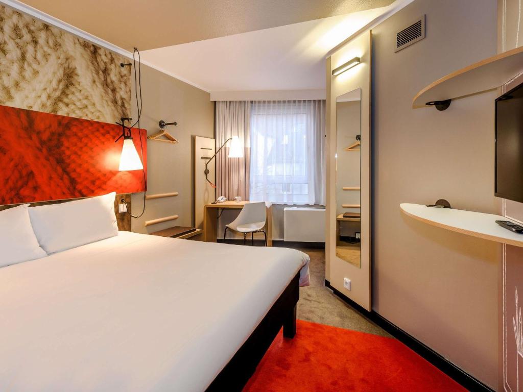 a hotel room with a large bed and a desk at ibis Hotel München City in Munich