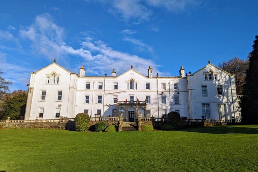 duży biały dom z zielonym trawnikiem w obiekcie Court Colman Manor w mieście Bridgend