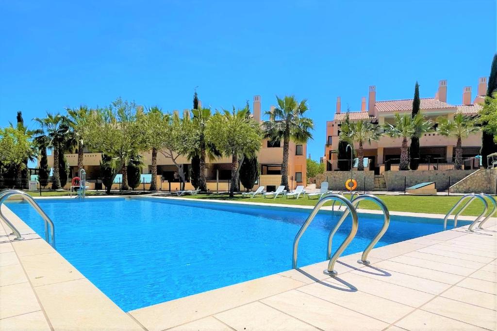 a swimming pool at a resort with trees and buildings at Relax House Murcia in Fuente-Álamo de Murcia