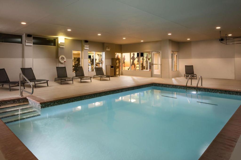 a large swimming pool in a hotel with chairs and tables at Hyatt Place Oklahoma City Bricktown in Oklahoma City