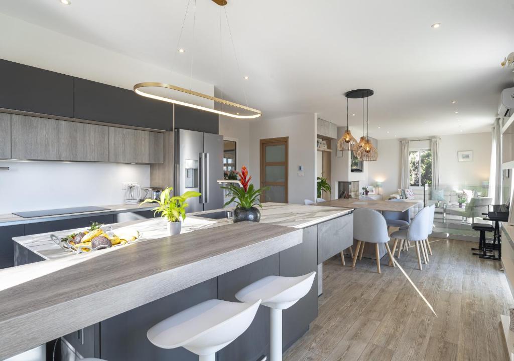une cuisine avec un grand îlot avec des tabourets blancs dans l'établissement Villa Casa C Valbonne, à Valbonne