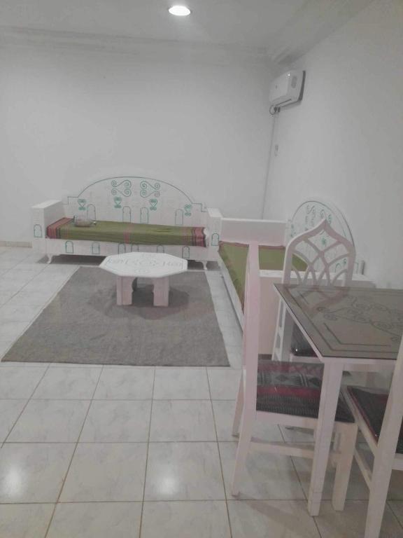 um quarto com um sofá, uma mesa e um banco em Appartement yakine em Midoun