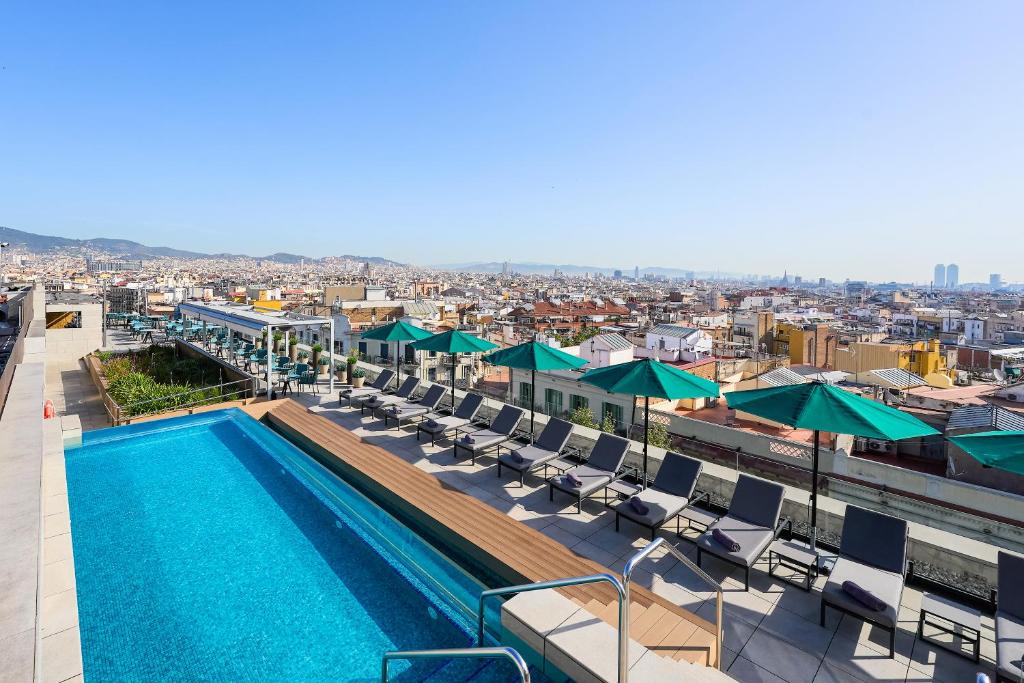 una piscina en la parte superior de un edificio con sillas y sombrillas en InterContinental Barcelona, an IHG Hotel en Barcelona