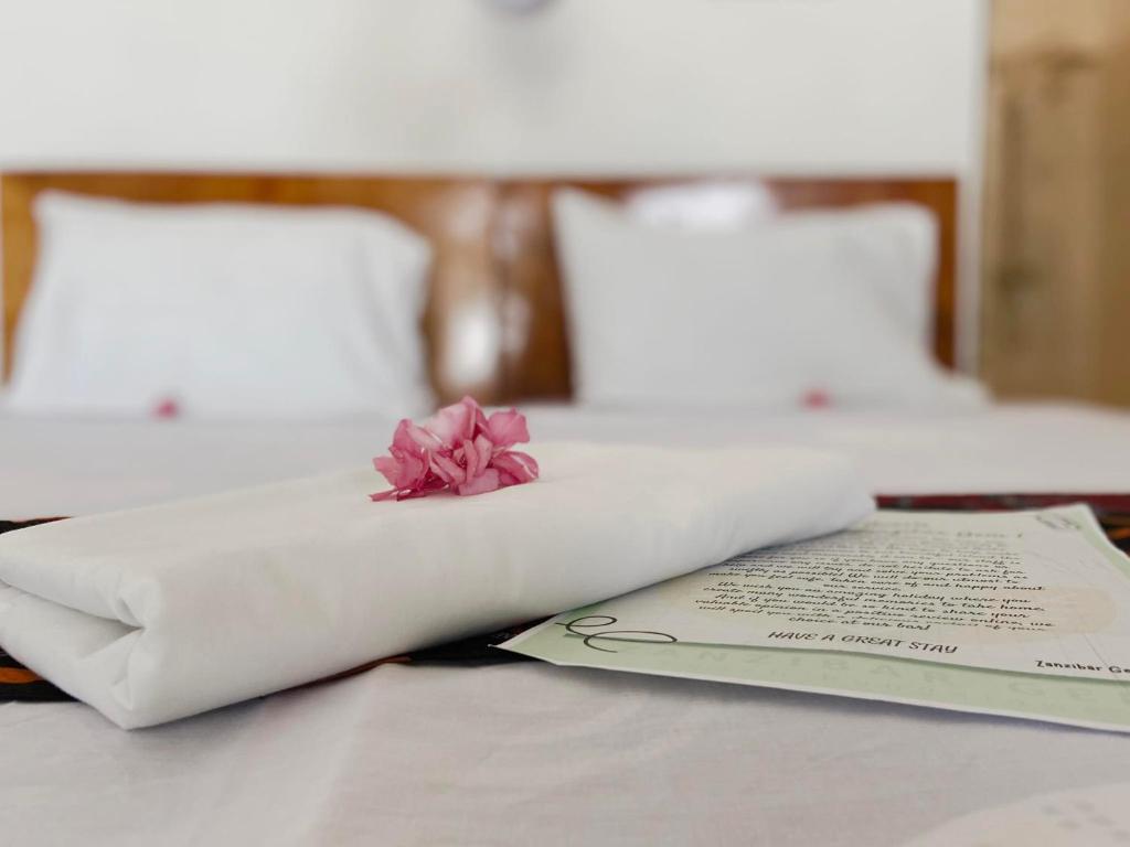 a book and a flower on a table with two beds at Zanzibar Gem Beach Bungalows in Bwejuu