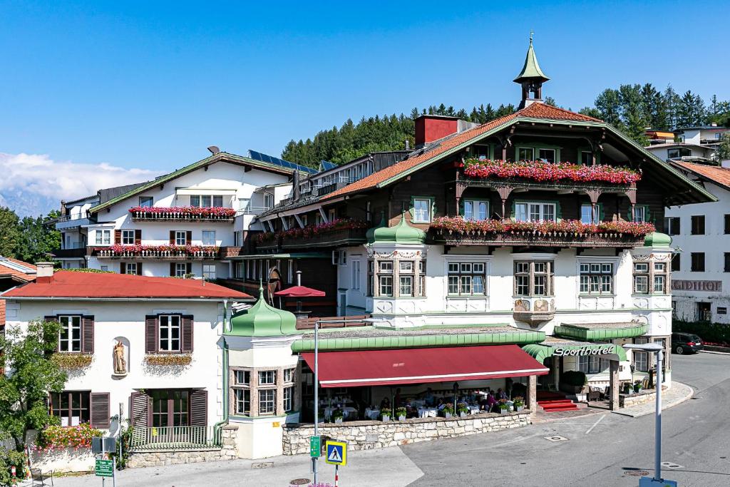 duży budynek z wieżą zegarową na górze w obiekcie Sporthotel Igls w mieście Innsbruck