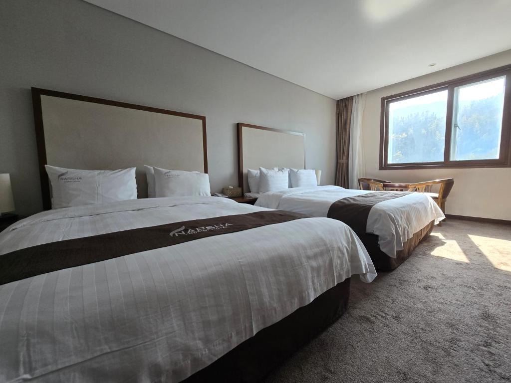 a hotel room with two beds and a window at Yeosu Narsha Hotel in Yeosu