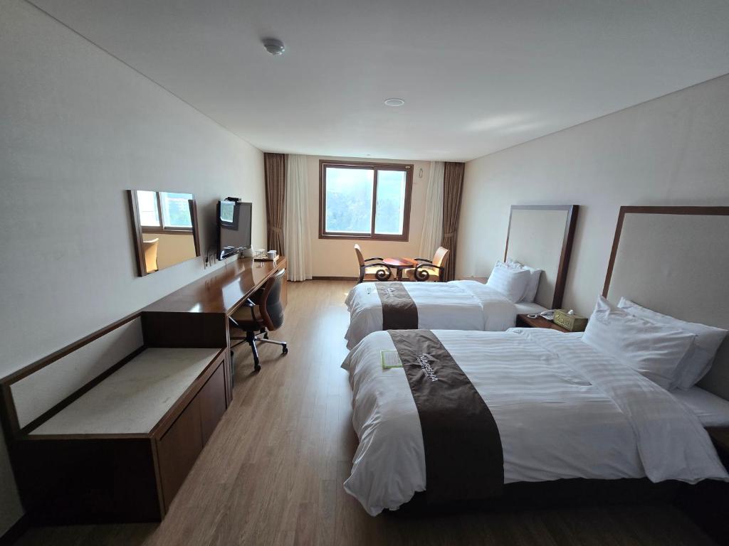 a hotel room with two beds and a television at Yeosu Narsha Hotel in Yeosu