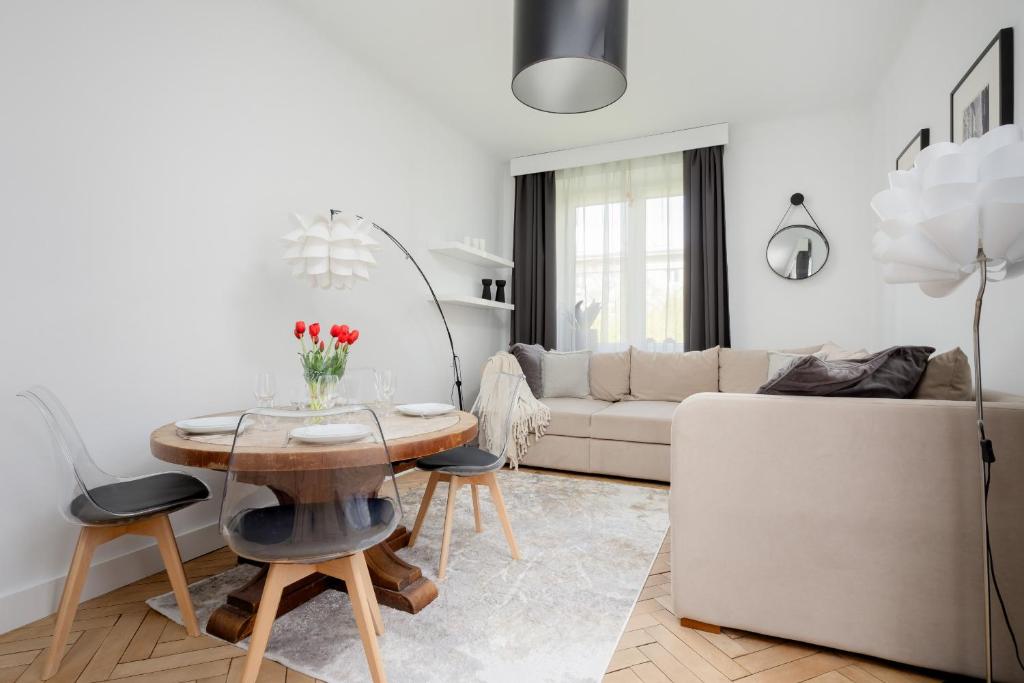 ein weißes Wohnzimmer mit einem Tisch und einem Sofa in der Unterkunft Beautiful & Modern Apartment near the City Center by Renters in Warschau