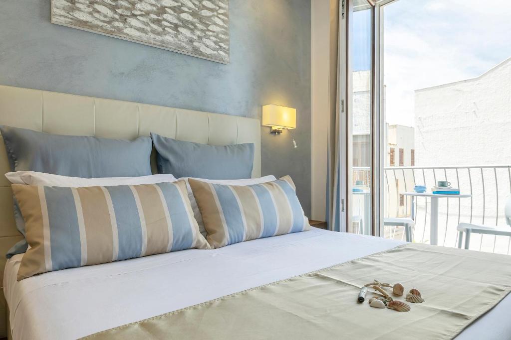 a bedroom with a bed with pillows and a balcony at Hotel Soffio D'Estate in San Vito lo Capo