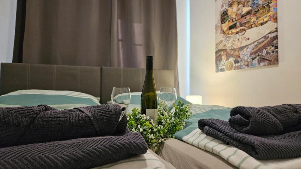 Una cama con una botella de vino y dos copas en APARTMENTS RATZERSDORFER SEEN in 3100 SANKT PÖLTEN en Sankt Pölten