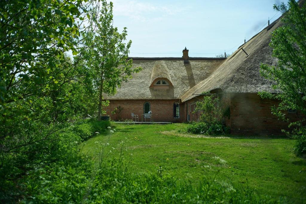 an old brick house with a grass yard at Sibyllenhof, Denkmalgeschütztes Reetdachanwesen in ruhiger Alleinlage in Siekbüll