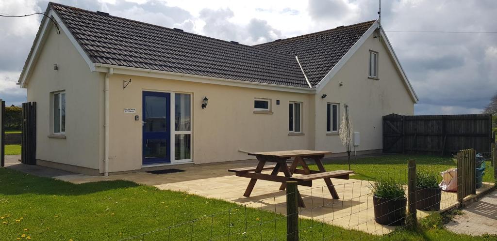a small white house with a picnic table in the yard at Llainfawr Cottage Apartment Fishguard in Letterston