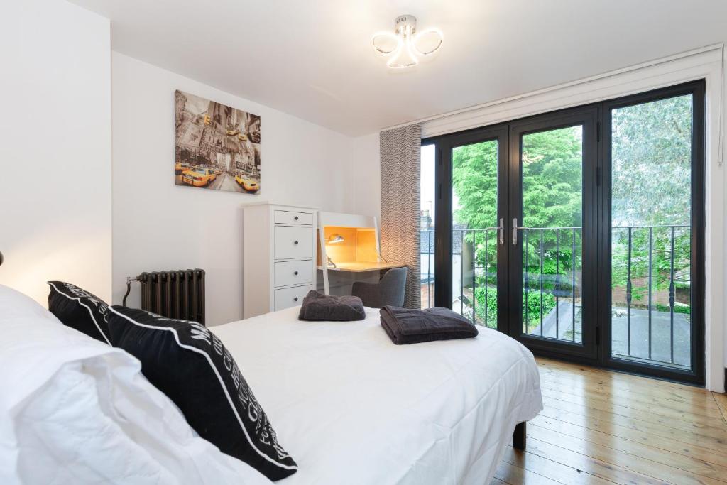 um quarto com uma grande cama branca com almofadas pretas em Trendy Terraced House in Central Oxford em Oxford