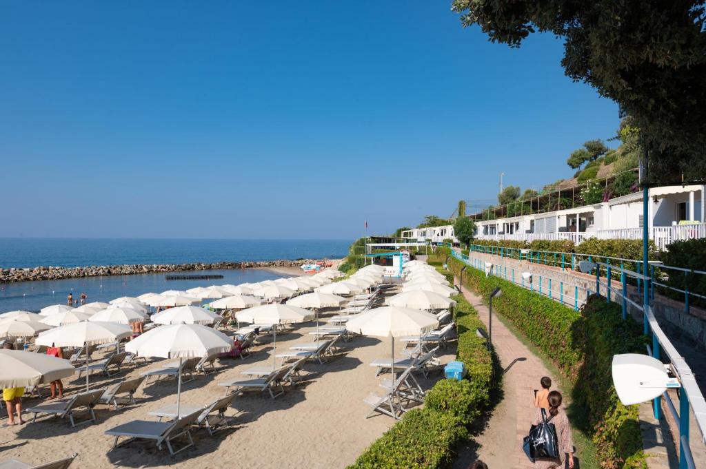 una fila de sombrillas y sillas en una playa en Resort Baia del Silenzio, en Pisciotta
