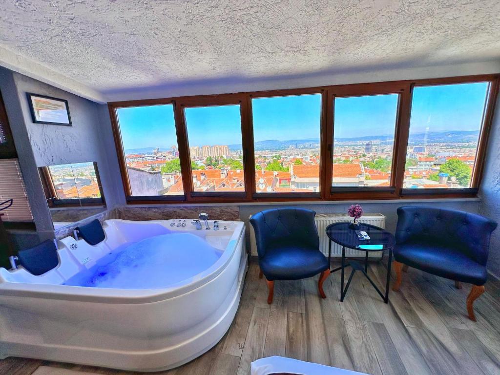a large bathroom with a large tub and some chairs at Pera Pansiyon in Bursa