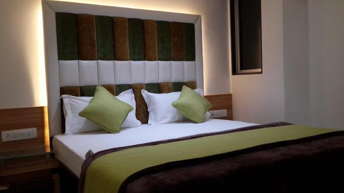 Un dormitorio con una cama grande con almohadas verdes y blancas en Lee Grande en Gūduvāncheri