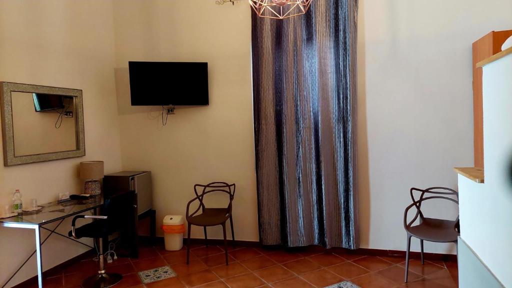 a room with a curtain with chairs and a television at Il Mirto E La Rosa in Arenella