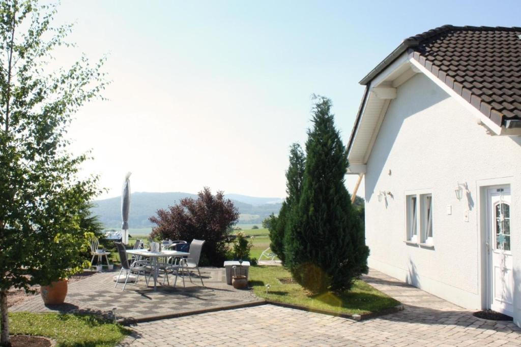 Ein weißes Haus mit einer Terrasse und einem Tisch in der Unterkunft Gemütliche Maisonette-Wohnung mit Fußbodenheizung in Berndorf