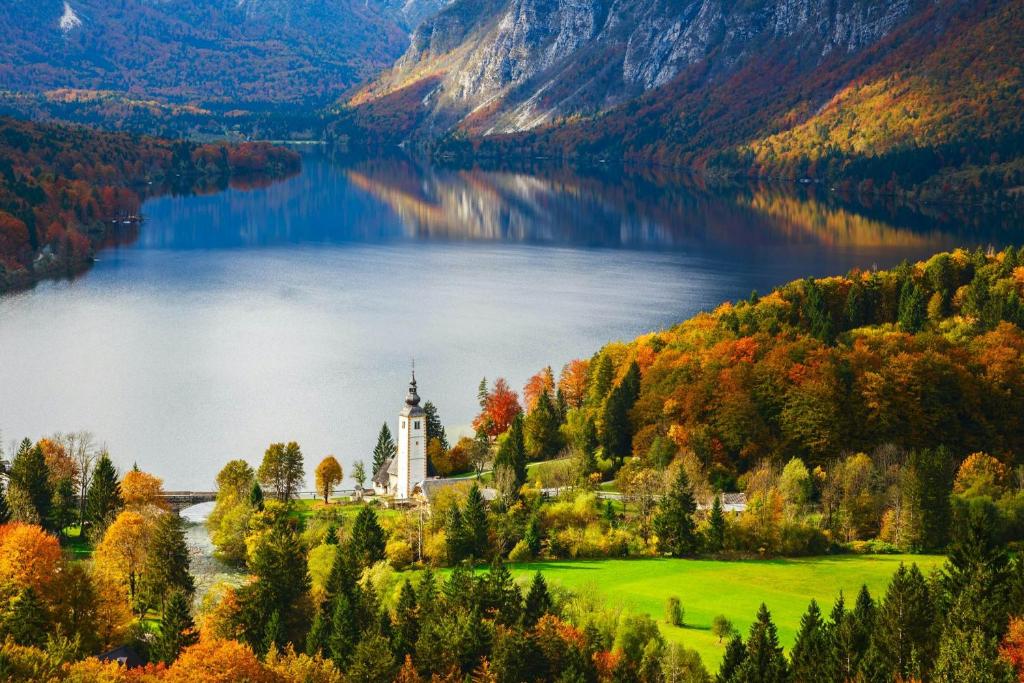 a castle on a island in a lake with trees at APARTMA VODNIK in Bohinj