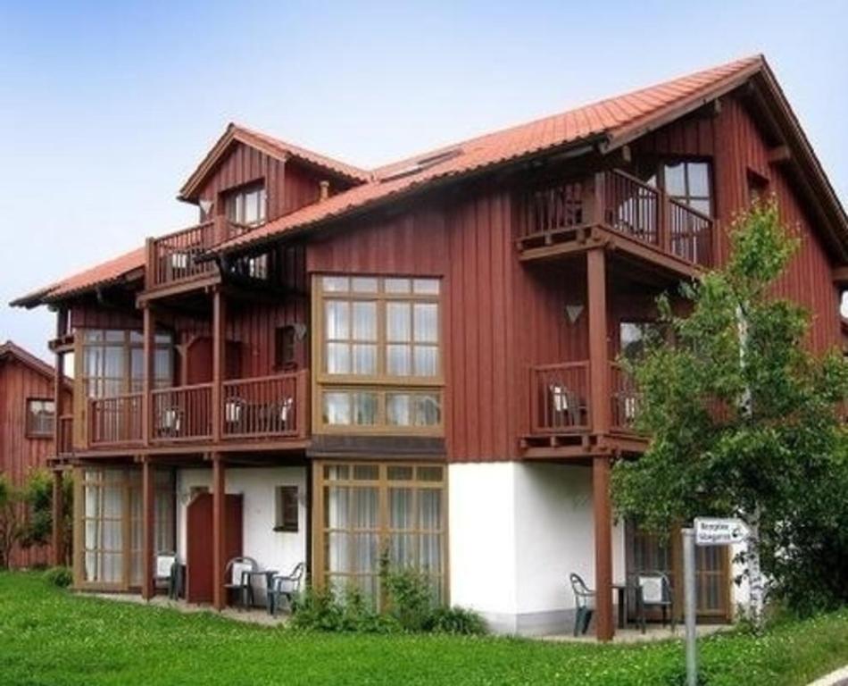 un grand bâtiment rouge avec balcon. dans l'établissement Apartment Bayrischer Wald am Golfclub im Feriendorf Glasgarten, à Rötz