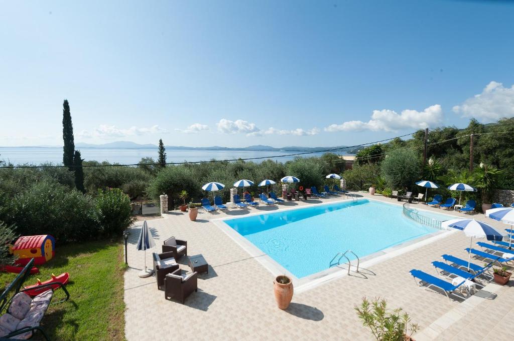 una gran piscina con sillas y sombrillas en Crystal Blue Aparthotel, en Barbati