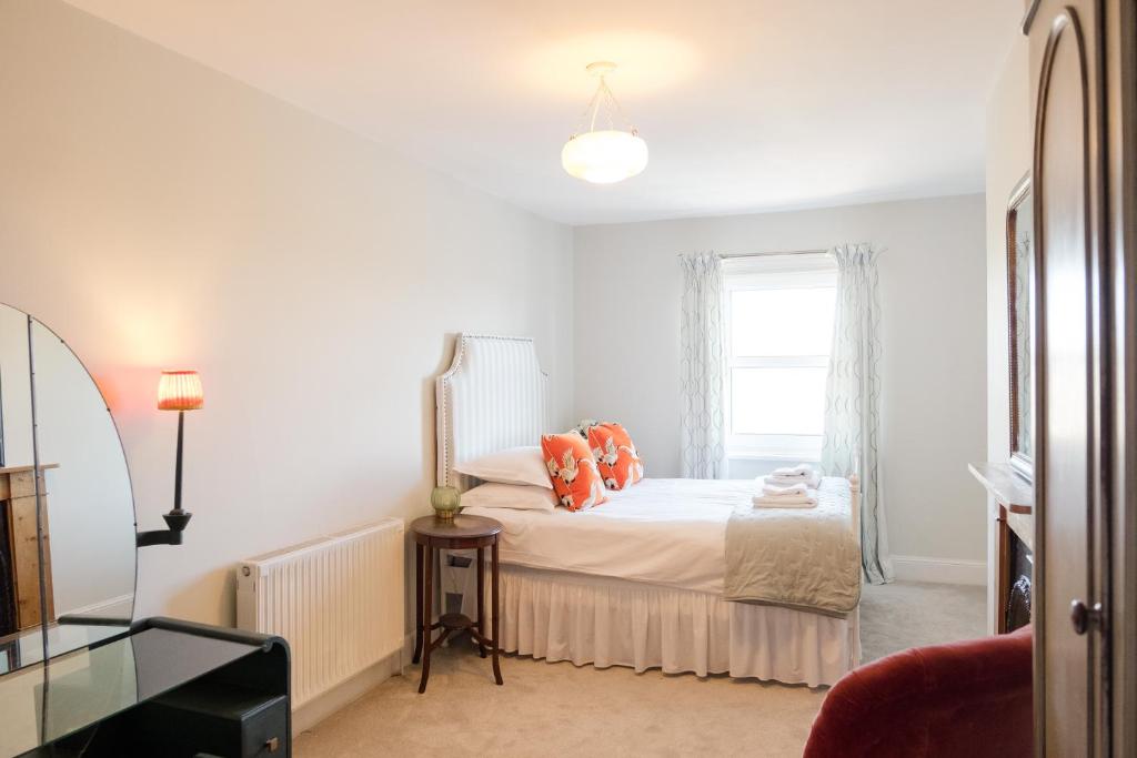 Southsea, Portsmouth - Two Bedroom Apartment - Newly Refurbished Throughout - Treetop Sea Views في بورتسماوث: غرفة نوم مع سرير مع وسائد برتقالية ونافذة