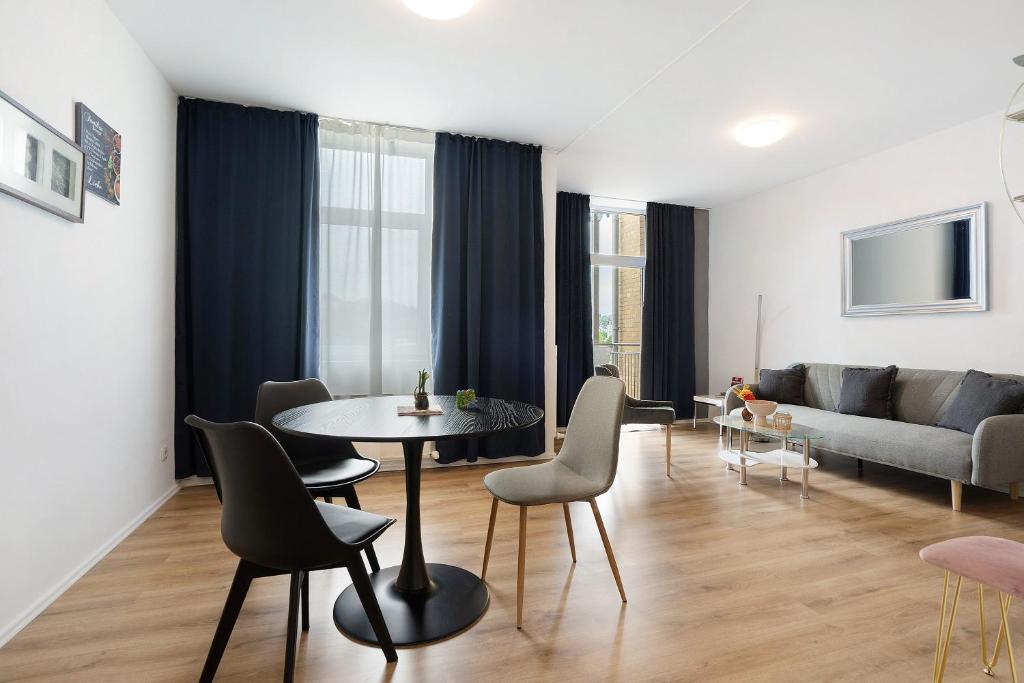 een woonkamer met een tafel en stoelen en een bank bij Appartmenthaus - Wohnung C in Plauen
