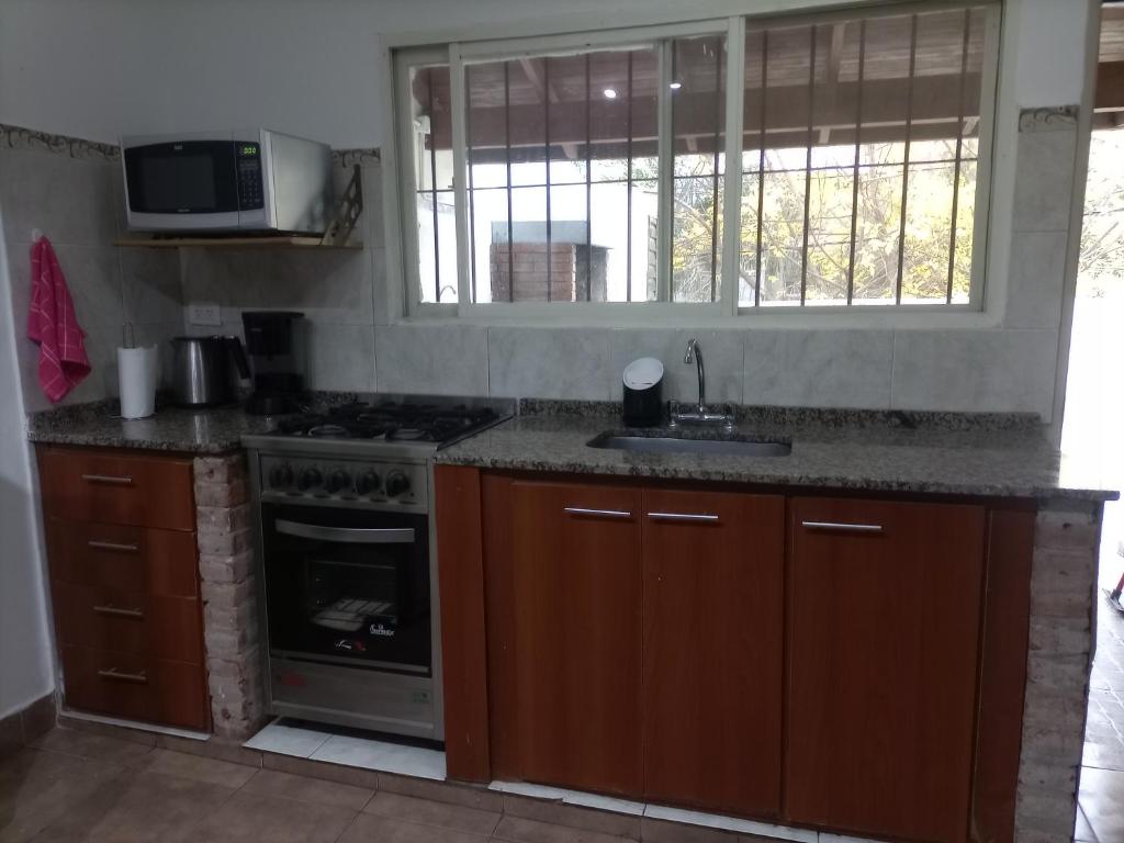 a kitchen with a stove and a sink and a microwave at Aero (a 8 cuadras del Colegio Militar de la Nación) in El Palomar