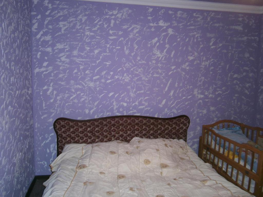 a bed in a bedroom with a purple wall at Dava in Gyumri
