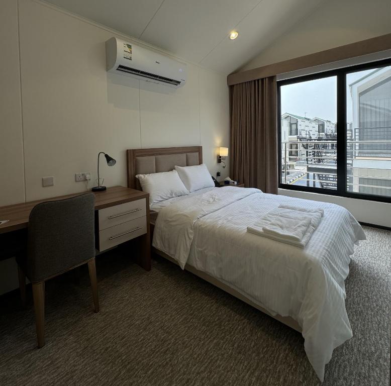 a bedroom with a bed and a desk and a window at Tamimi Geshla Residency in Al ‘Aqrabīyah