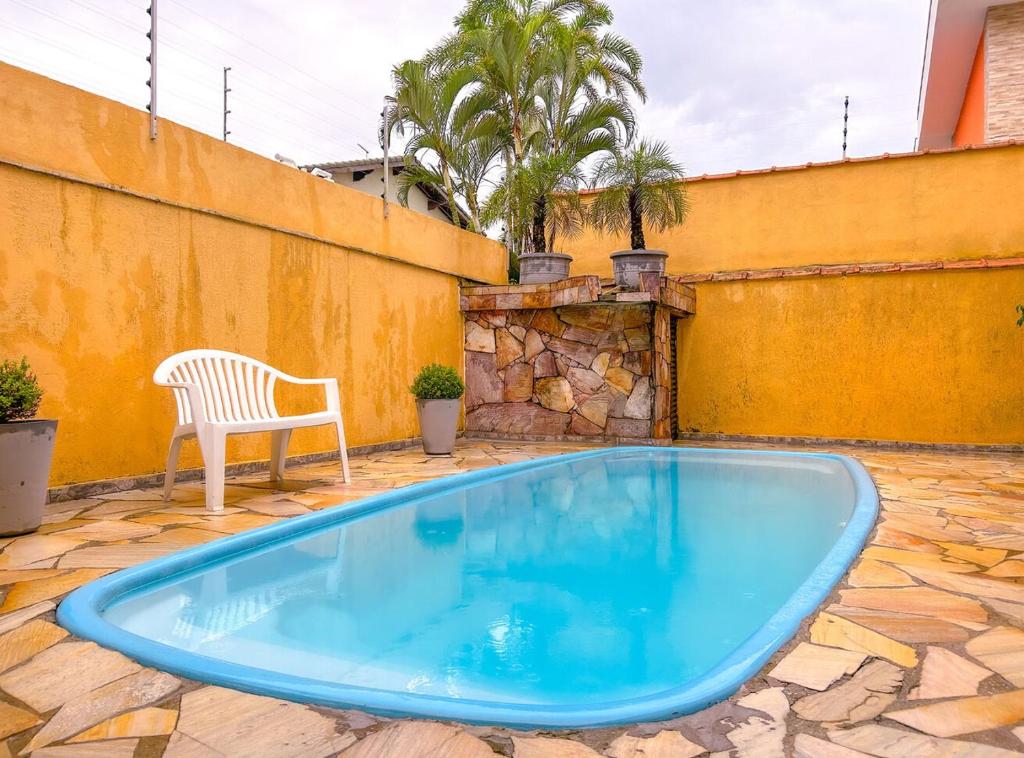 - une piscine bleue avec une chaise blanche à côté d'un bâtiment dans l'établissement Incrivel casa a 200m da Praia da Enseada Bertioga, à Bertioga