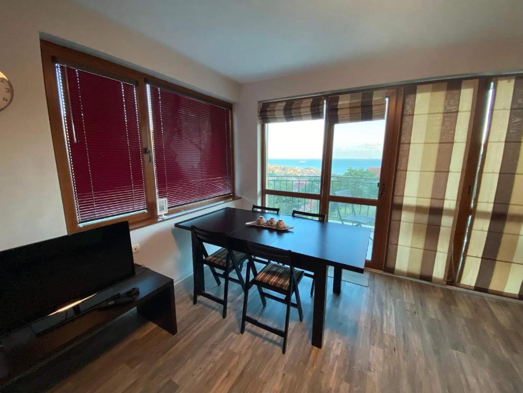 ein Esszimmer mit einem Tisch und einigen Fenstern in der Unterkunft Apartments Vista in Baltschik