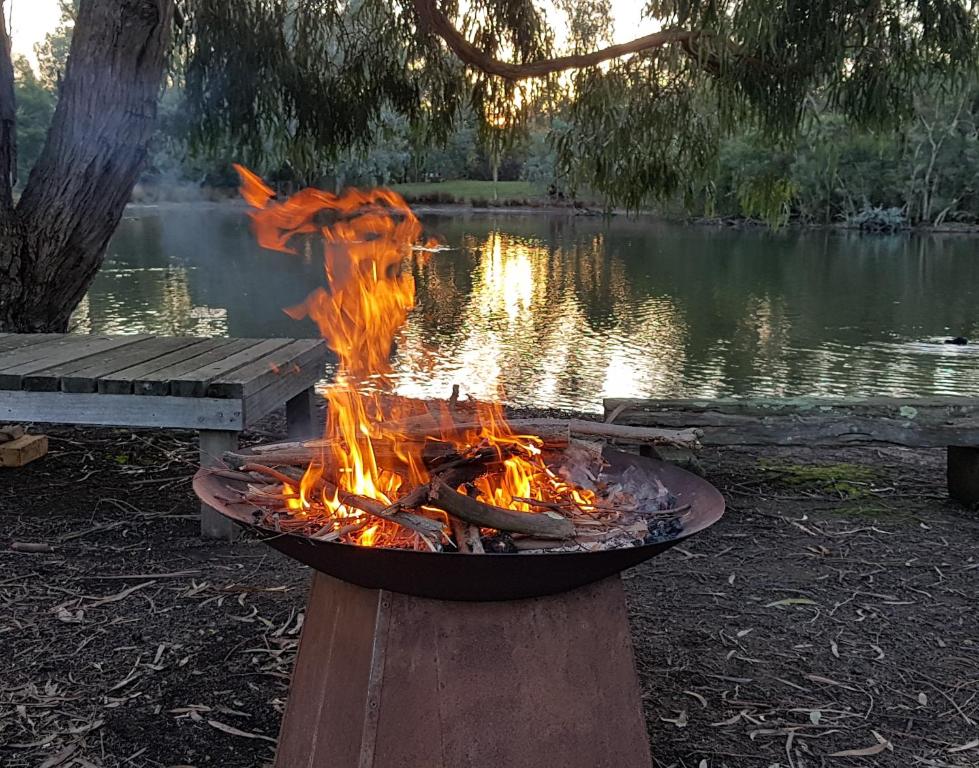 uma fogueira em frente a um lago em The Burrow at Wombat Bend em Dixons Creek