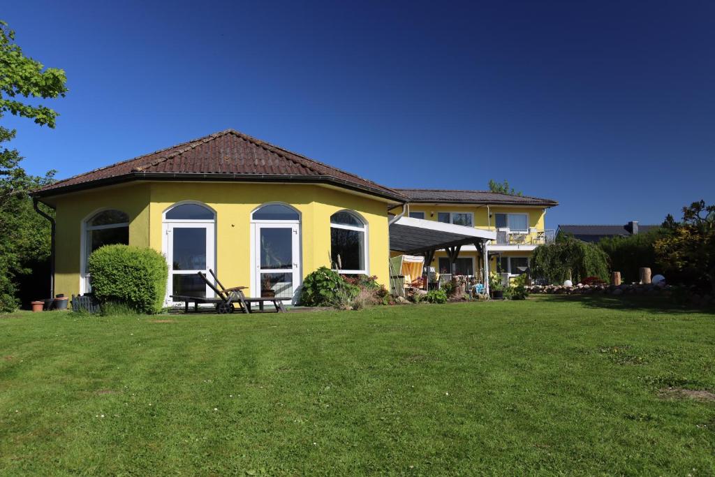 una casa amarilla con césped delante en Apartmenthaus Wattwurm, en Friedrichskoog