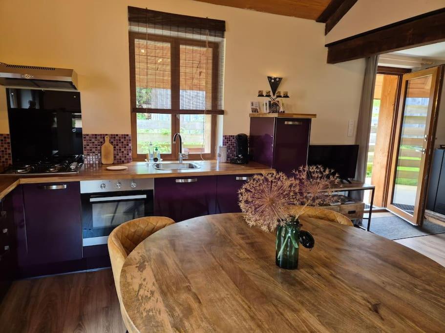a kitchen with a wooden table with a vase of flowers at Les Vergers d'Epona "Fremifontaine VOSGES" in Frémifontaine