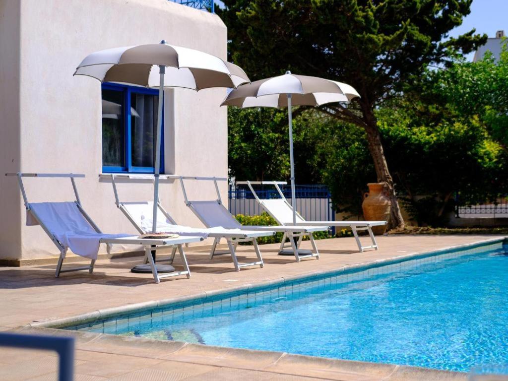 2 sillas y sombrillas junto a una piscina en Azzurro Holiday Villas, en Peyia