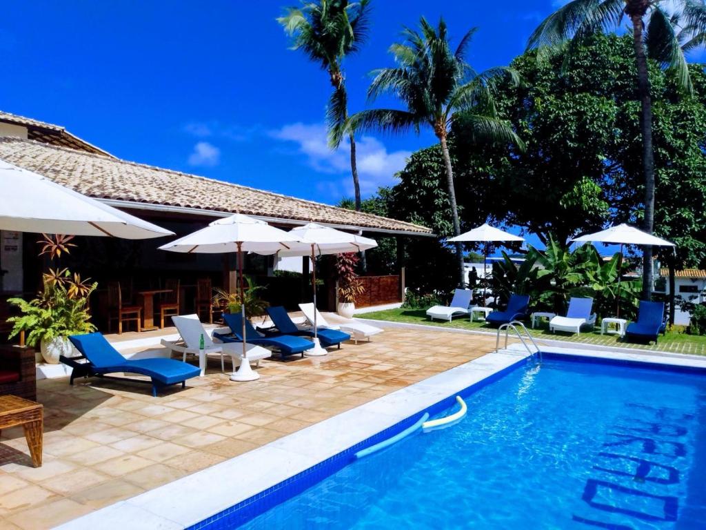 a swimming pool with lounge chairs and umbrellas at Hotel Pousada Salvador Paradise in Lauro de Freitas