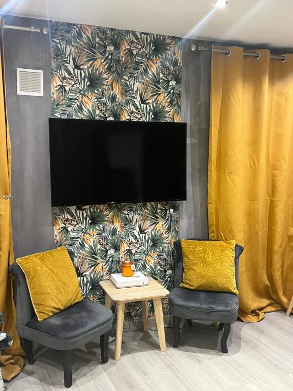 2 chaises et une table avec une télévision murale dans l'établissement Chez fati, à Paris