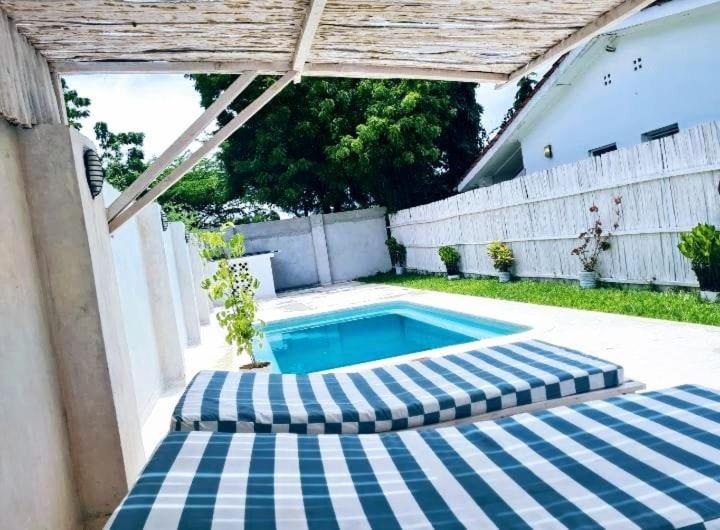 a swimming pool with two umbrellas in a backyard at 2 Bedroom Holiday Cottages Bofa Road, Kilifi in Kilifi