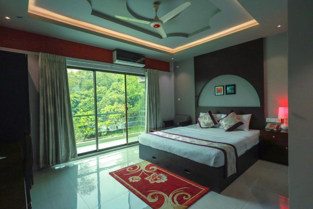 ein Schlafzimmer mit einem Bett und einem großen Fenster in der Unterkunft D'more Sreemangal Hotel & Resort in Sreemangal