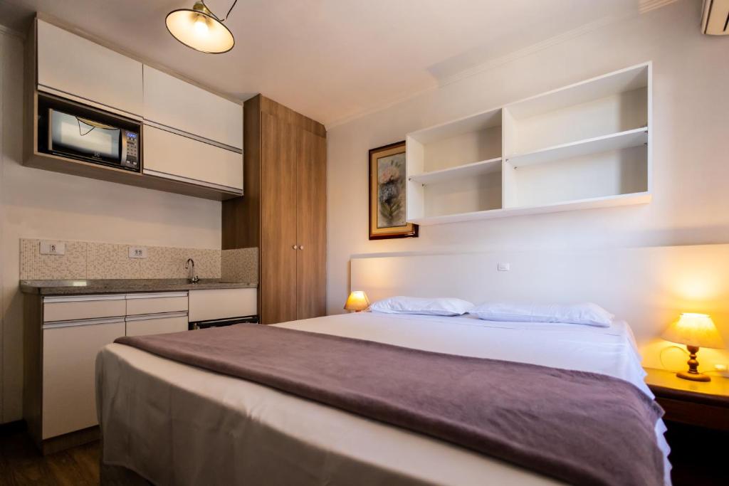 a bedroom with a large bed and a kitchen at Hotel Golden Star in Curitiba
