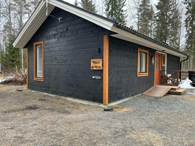 una pequeña casa negra con porche y puerta en Villa Alpaca Mökki - Laamatila, en Nokia