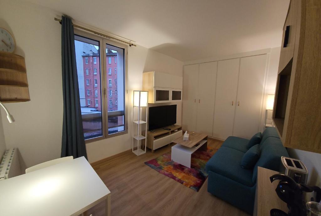 un salon avec un canapé bleu et une télévision dans l'établissement Studio Paris Clichy, à Clichy